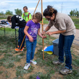 A volunteer is helping a group of kids with educational content outside. 