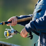 Person in a life jacket holds a fishing reel