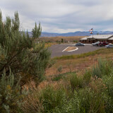 The visitor center is pictured in the distance on a landscape dotted with sage brush.